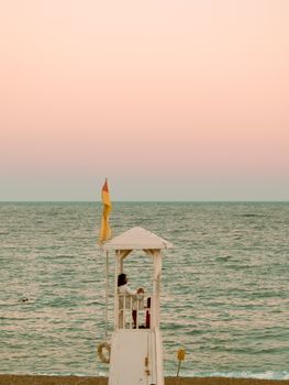 Tranquil scene of a lifeguard station with ocean view during sunset. Ideal for summer or travel themes.