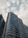 低角度仰视多云天空下的现代摩天大楼，展现城市建筑风貌