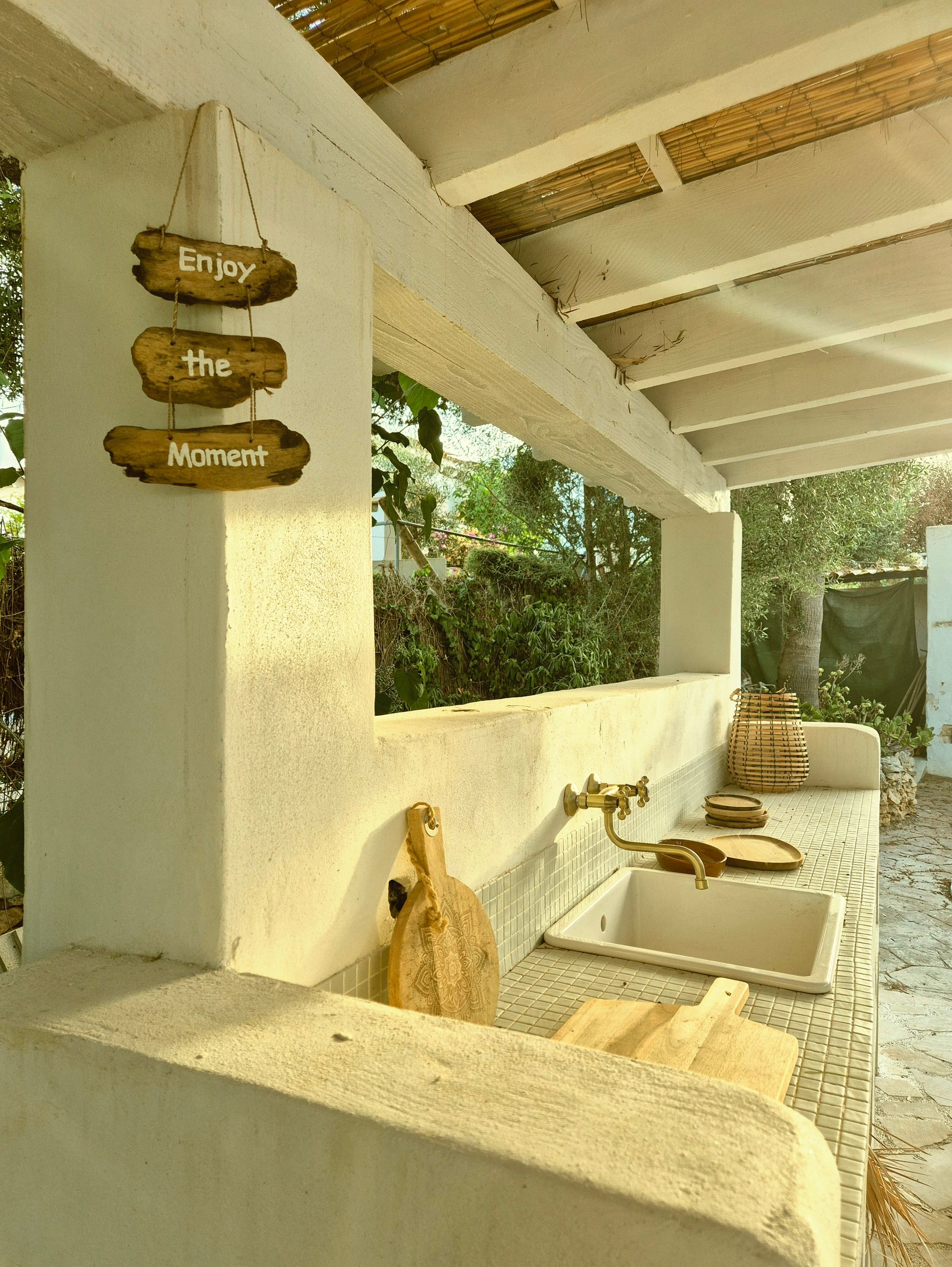 Outdoor kitchen with natural materials, wooden details, counter and garden setting