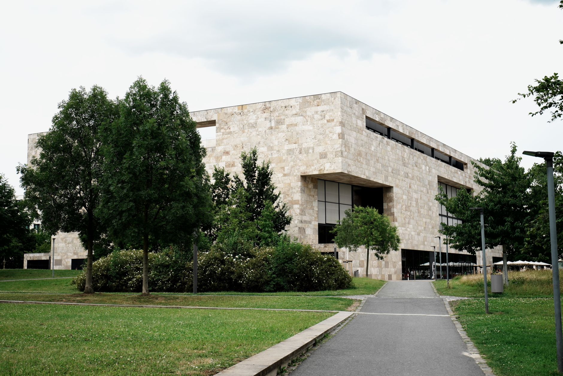 Contemporary stone building surrounded by greenery on a cloudy day.