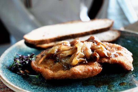Delicious schnitzel topped with caramelized onions, served with bread.