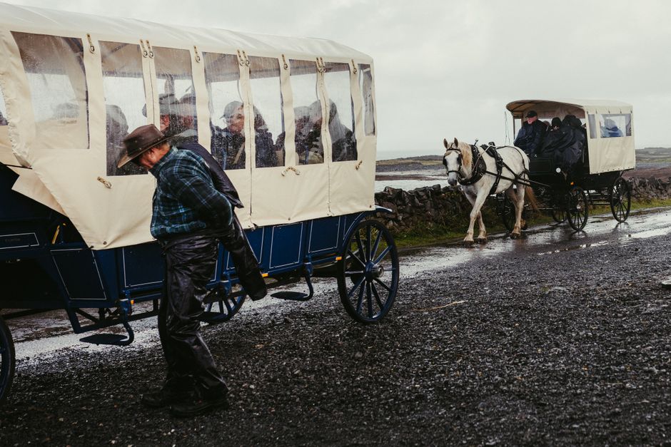 Horse-drawn carriages journey through a rainy road in County Galway, Ireland. Horse-drawn carriages journey through a rainy road in County Galway, Ireland.