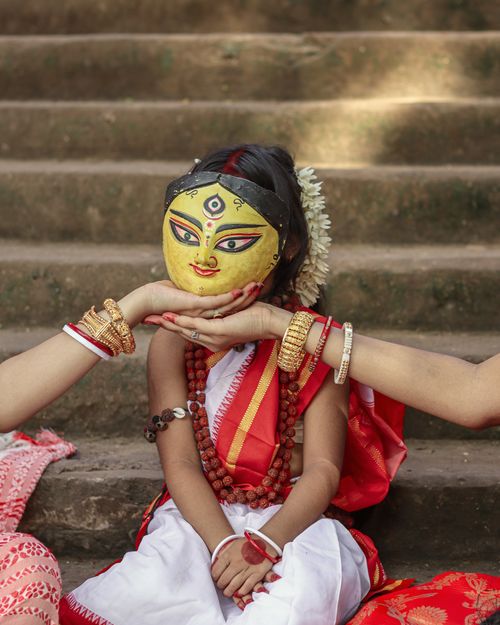 Free Young girl wearing traditional attire and a Durga mask, embodying Indian cultural celebration. Stock Photo