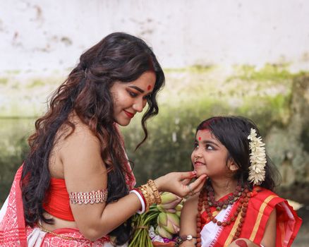 Charming portrait of a mother and daughter in traditional attire with joyful expressions.