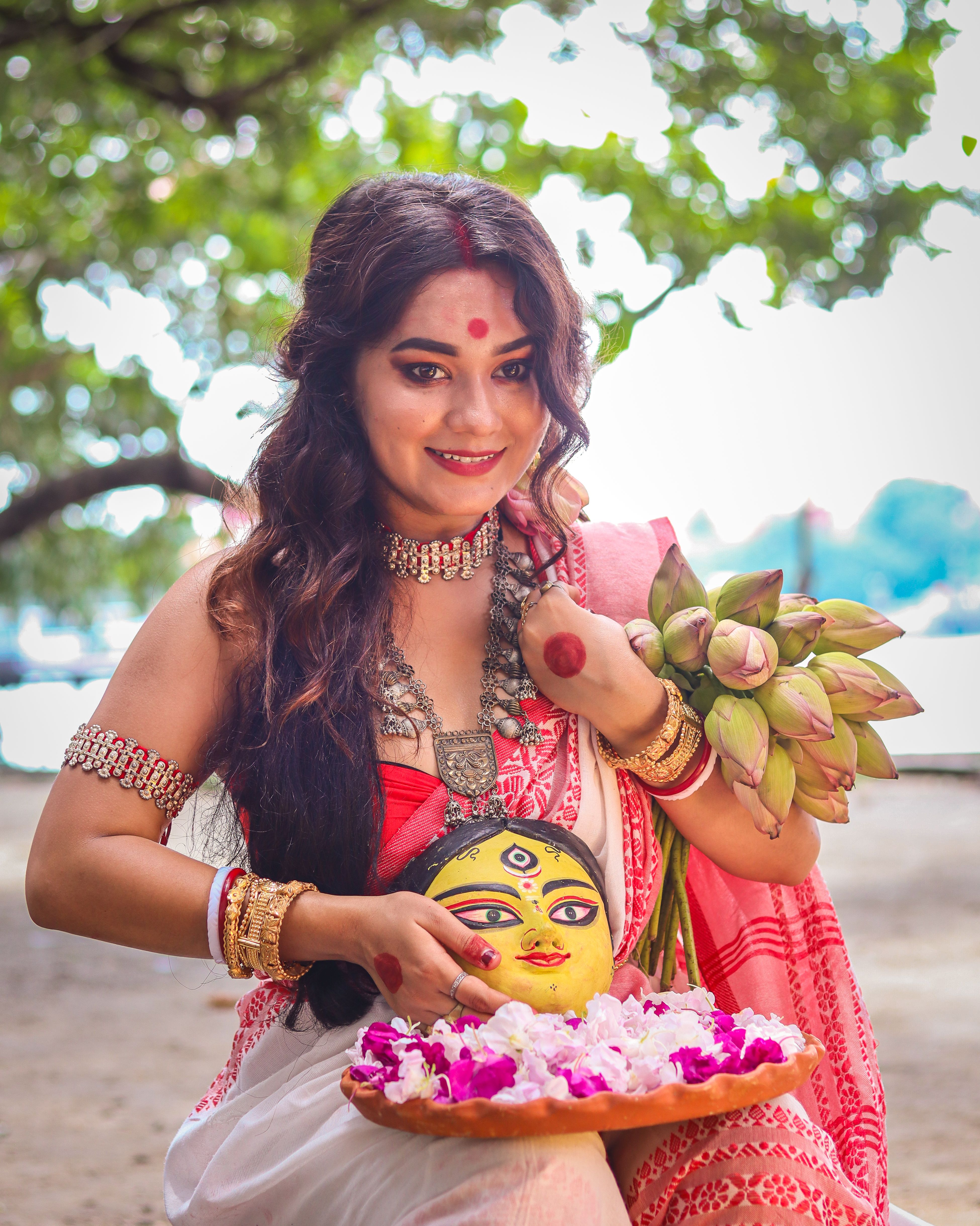 Woman practicing a traditional Indian ritual with flowers and religious symbols, wearing cultural attire.