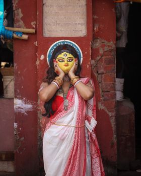 Indian woman in traditional saree holding a mask at a cultural heritage site in Kolkata.