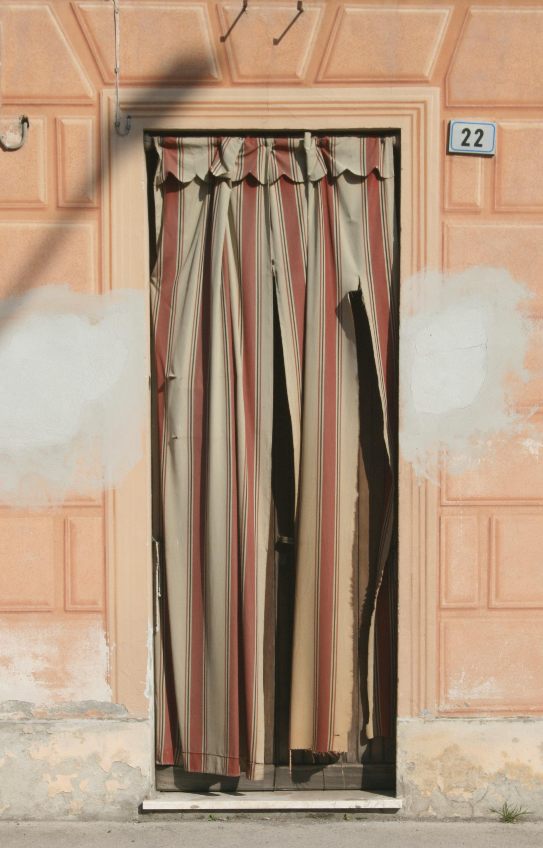 Weathered doorway with striped curtains in an old building facade.