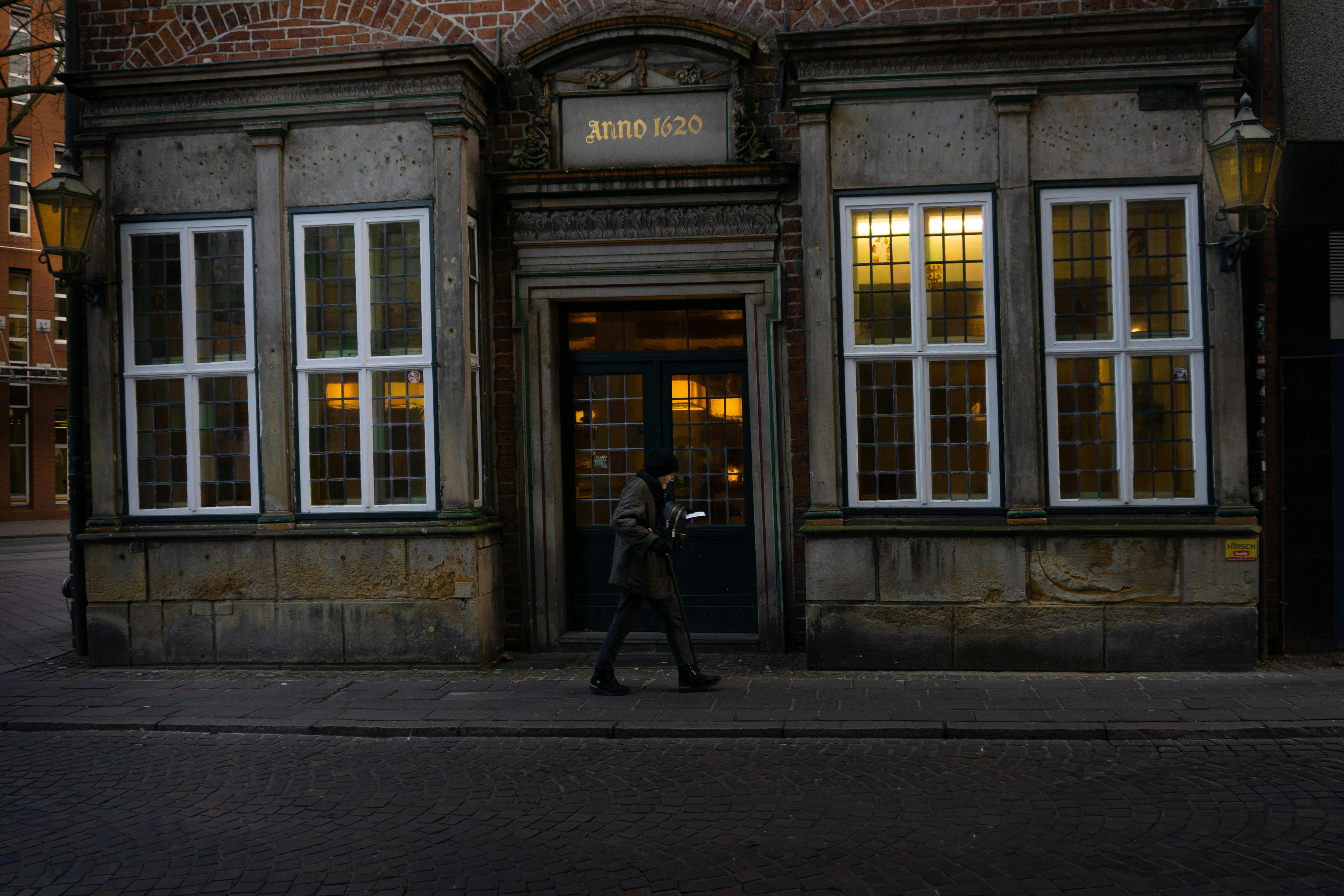 Gratis En person går forbi en historisk murbygning fra 1620 i Bremen, Tyskland, som viser frem arkitektur fra tidlig 1900-tall. Arkivbilde