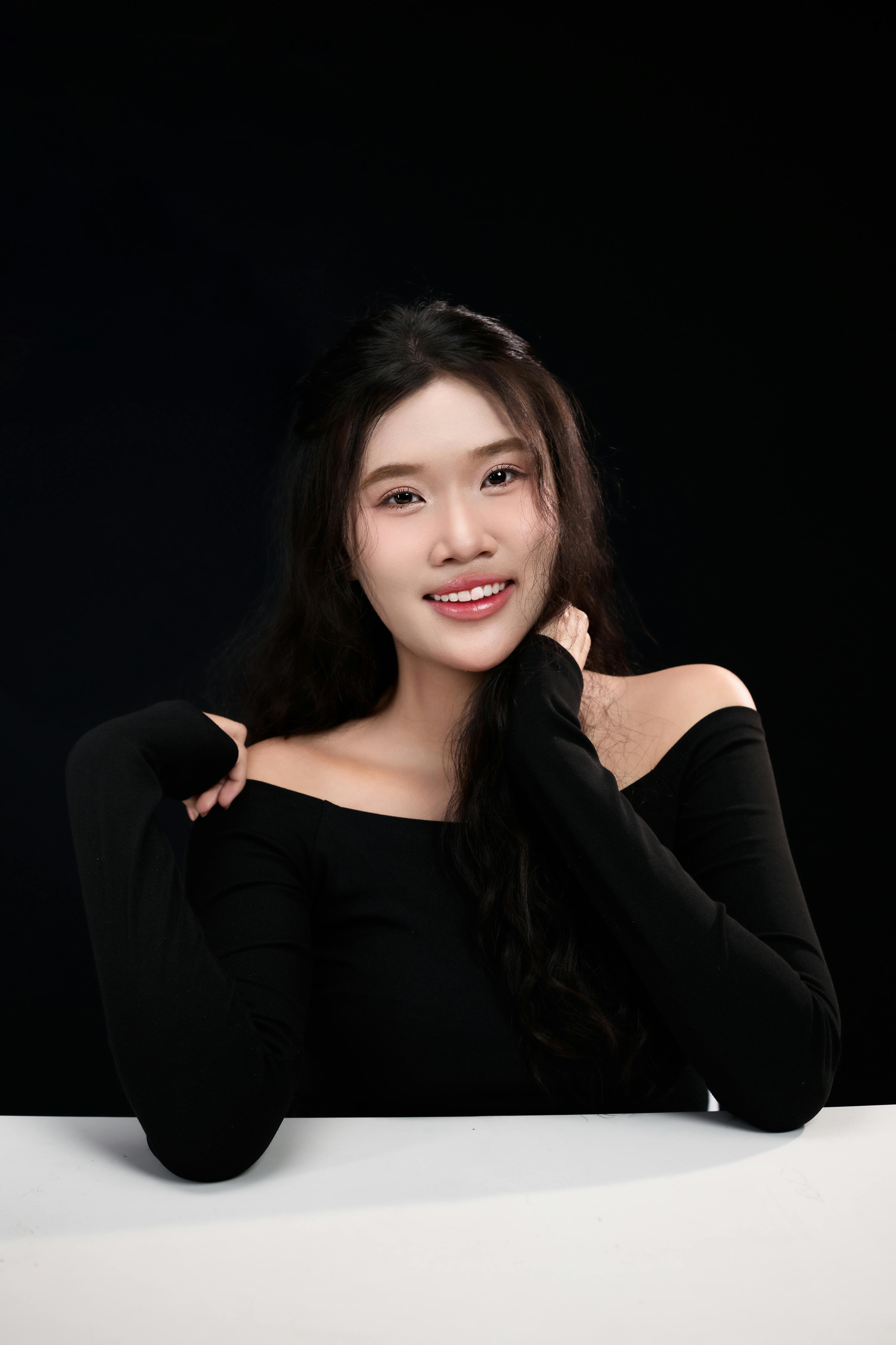 Ilmainen Viehättävä muotokuva aikuisesta naisesta mustassa asukokonaisuudessa tummaa taustaa vasten, joka esittelee eleganssia ja kauneutta. Kuvapankkikuva