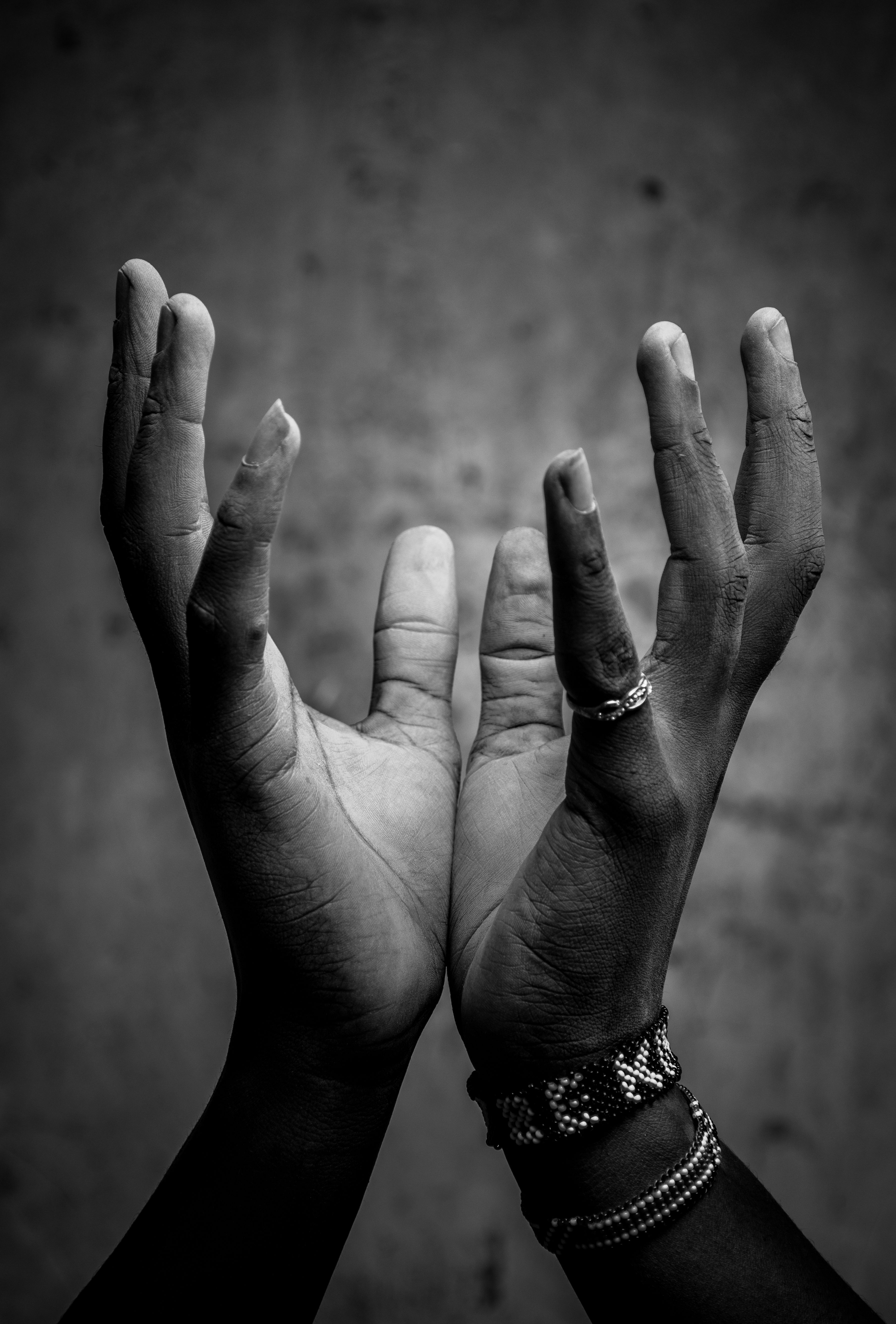 Black and white portrait of hands raised expressively, symbolizing hope and unity.