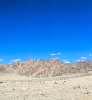 Stunning view of arid desert landscape and rocky mountains under a vibrant blue sky.