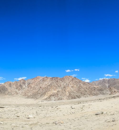Free Stunning view of arid desert landscape and rocky mountains under a vibrant blue sky. Stock Photo