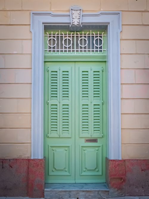 Free A beautiful pastel green doorway with ornate detailing and shutters, capturing Mediterranean charm. Stock Photo