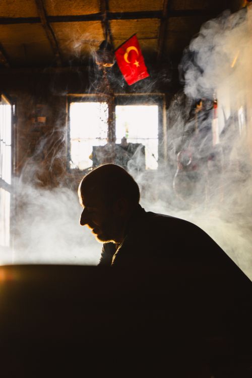 Free Dramatic silhouette of man in foggy room with Turkish flag and sunlight streaming through windows. Stock Photo