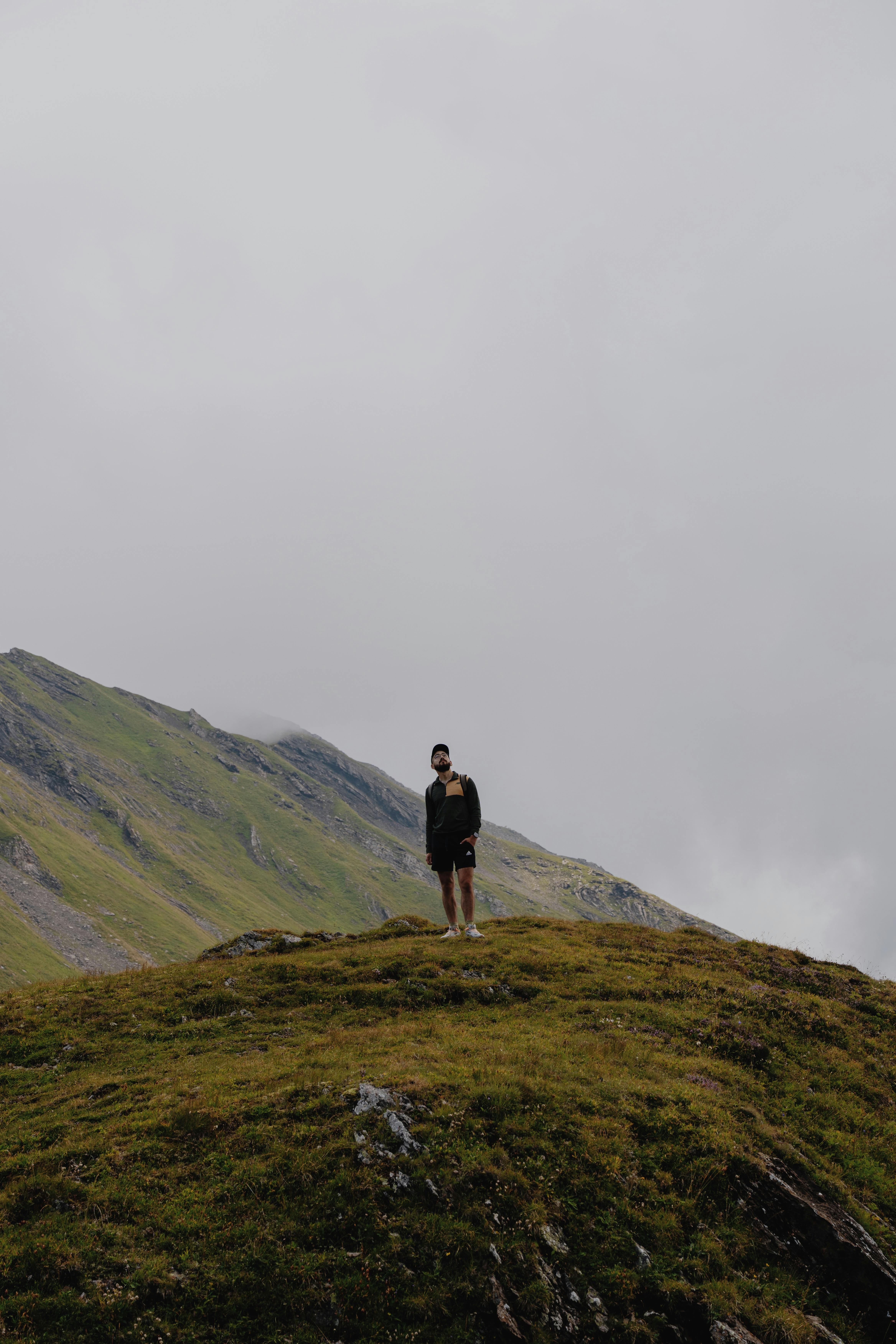 무료 흐린 하늘 아래, 스위스 그린델발트의 잔디 언덕에서 혼자 하이킹하는 사람. 스톡 사진