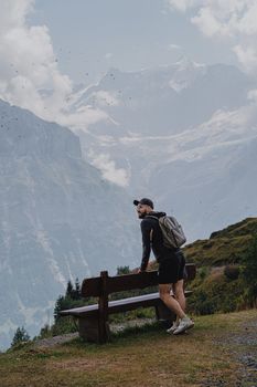 A male hiker resting on a bench with stunning views of the Swiss Alps in Grindelwald.
