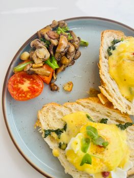 Eggs Benedict served on sourdough with sauteed mushrooms, broccoli, and cherry tomato.