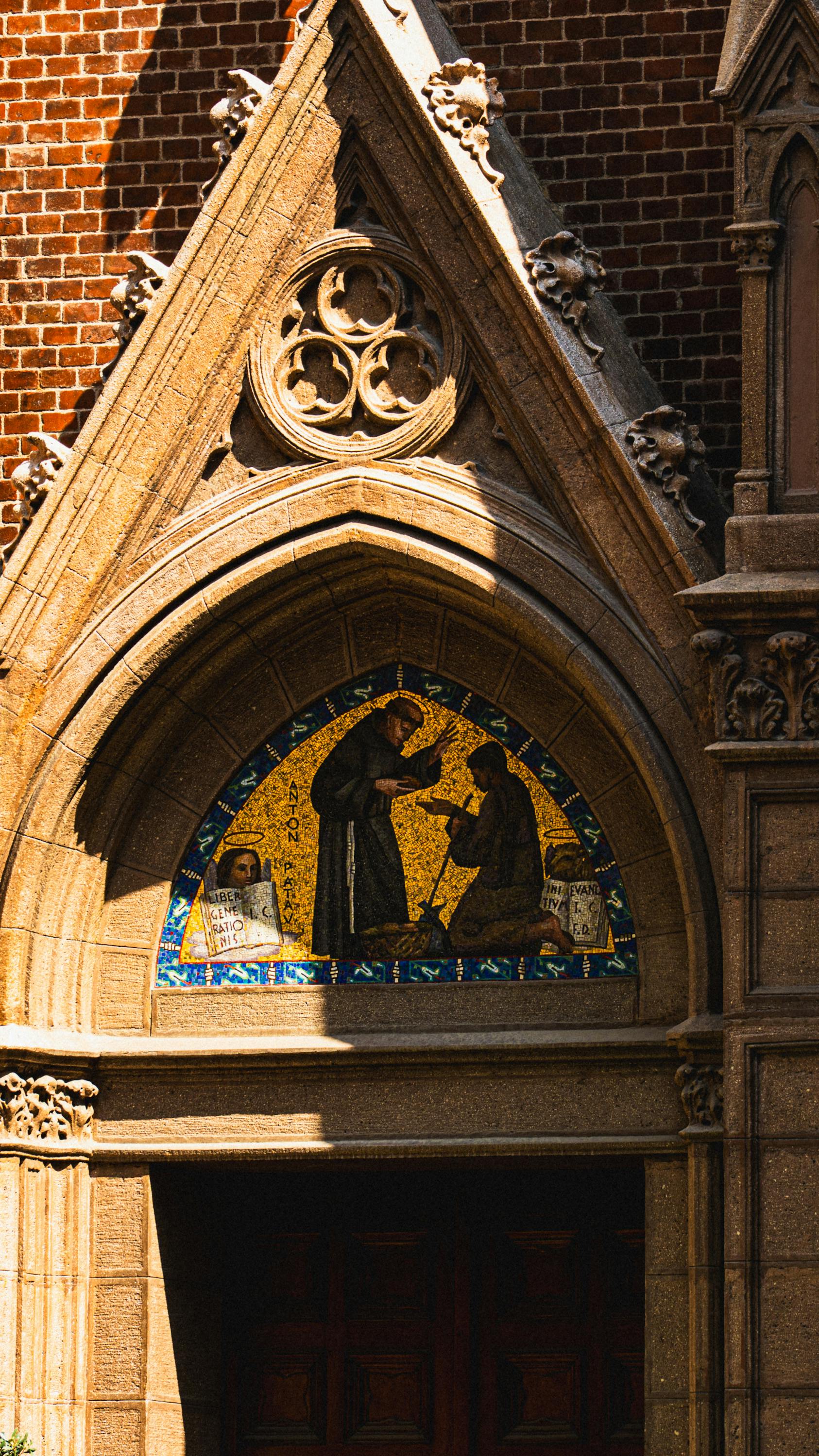 Ilmainen Auringon valaisema goottilainen kirkon sisäänkäynti, jossa on monimutkaista mosaiikkitaidetta ja yksityiskohtaista arkkitehtuuria. Kuvapankkikuva