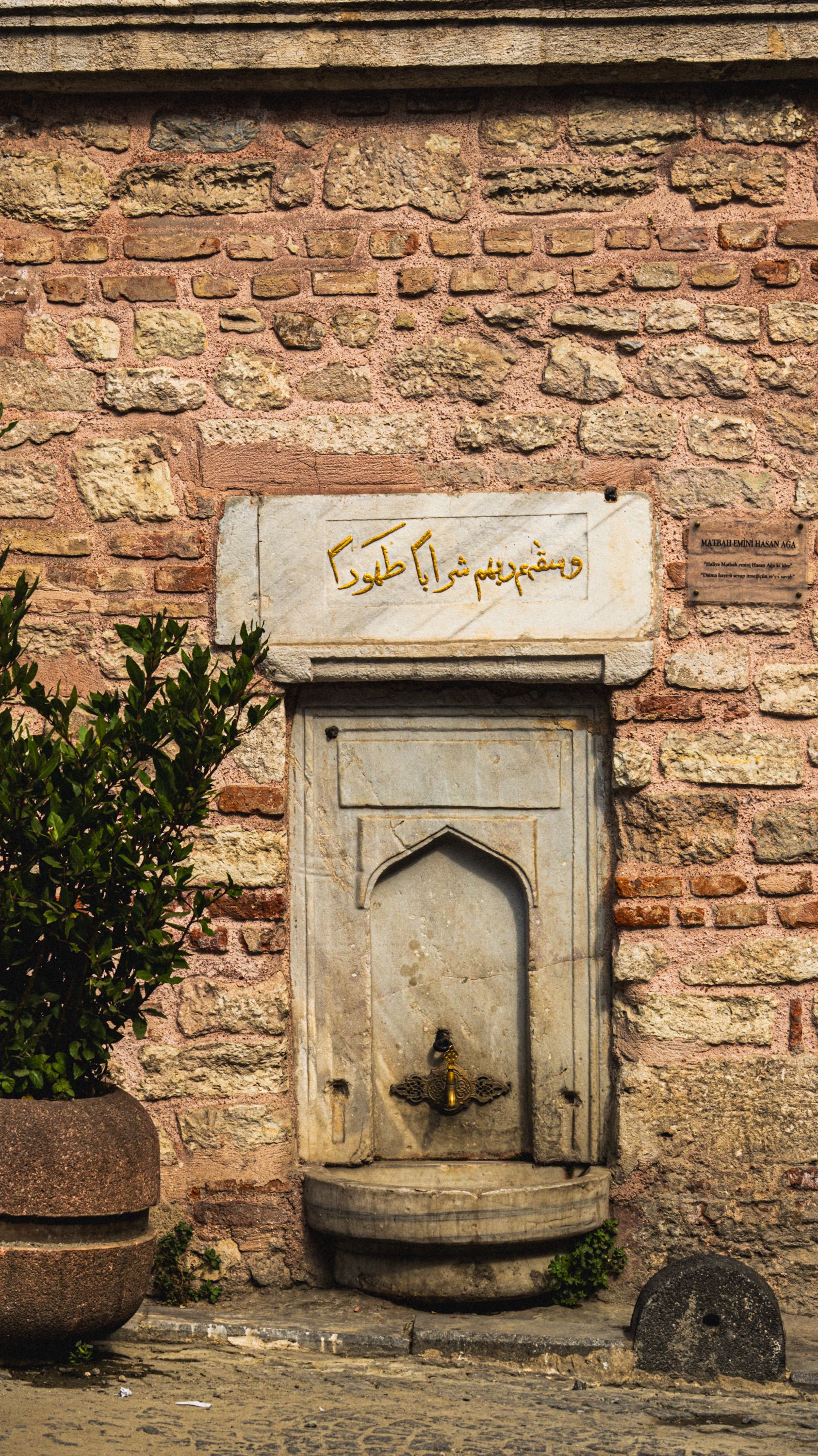 Old stone wall with a historic fountain and intricate script, evoking timeless charm.