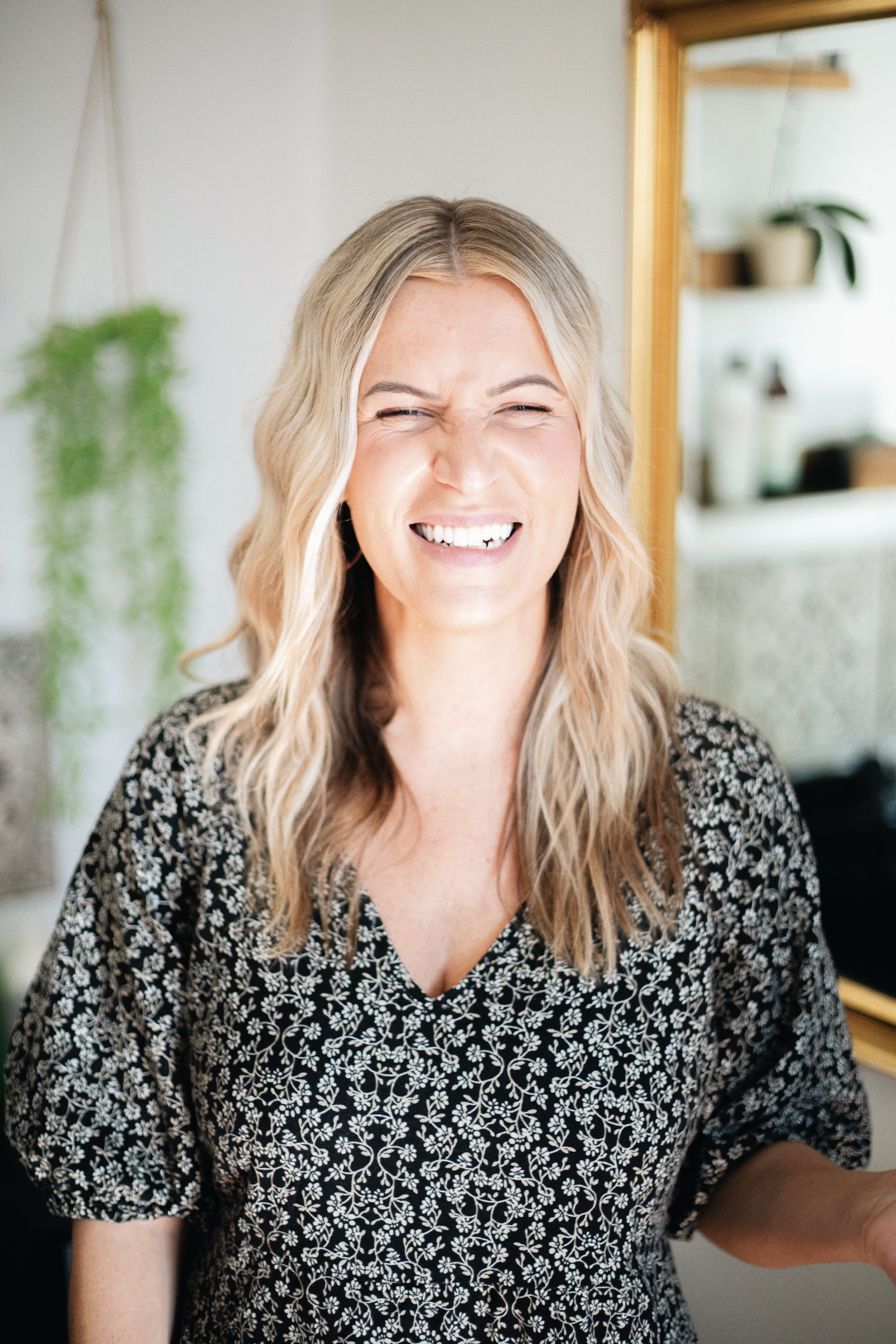 Candid portrait of a smiling woman with blonde hair in a stylish salon setting, embracing natural beauty.