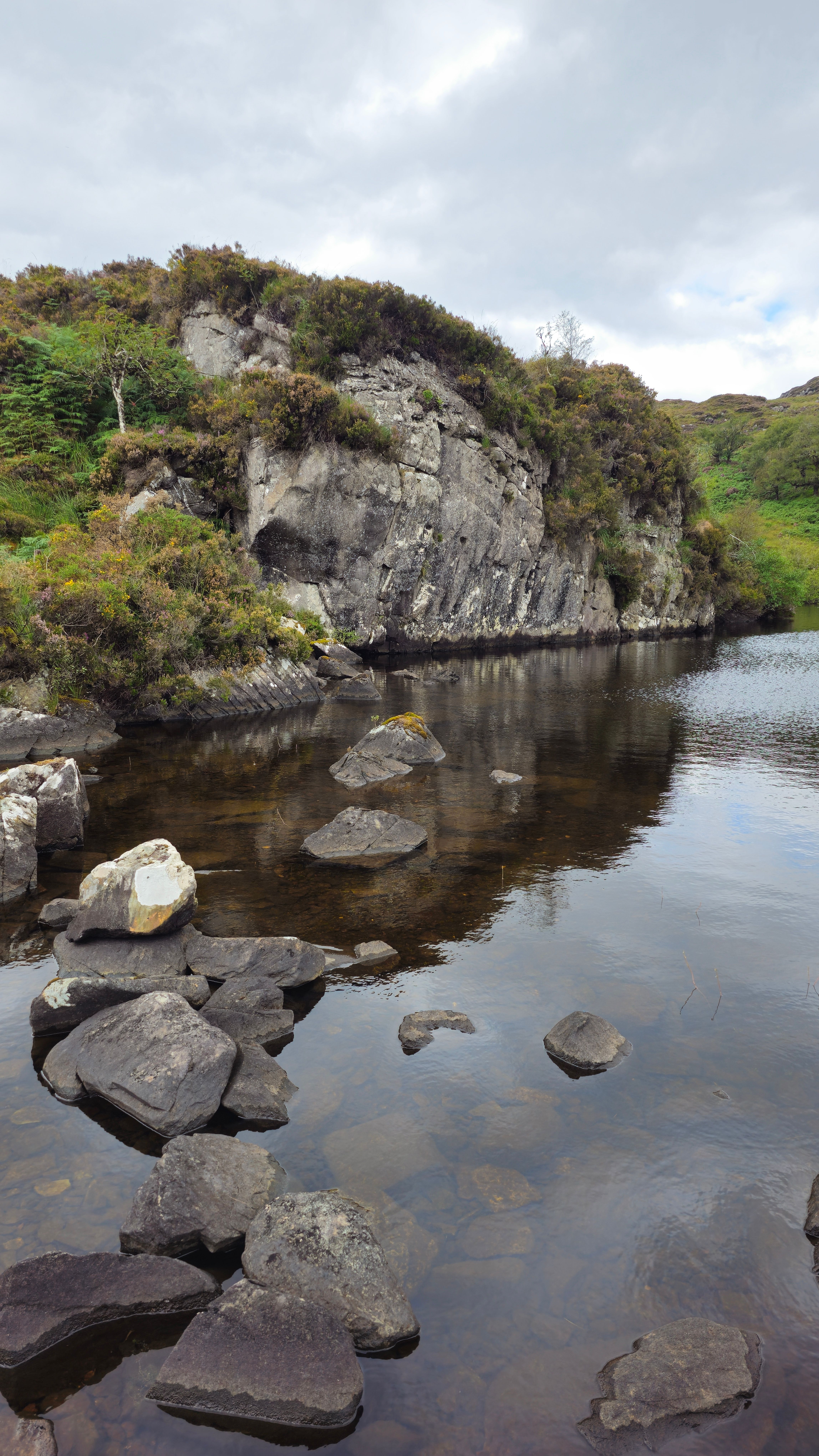 Picturesque rocky landscape with calm river and lush vegetation in Crohey Headland, Ireland.