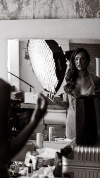Woman in dressing room with lighting setup, preparing for photography.