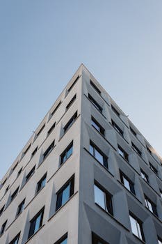 Low-angle view of a modern building with geometric patterns against a clear blue sky.