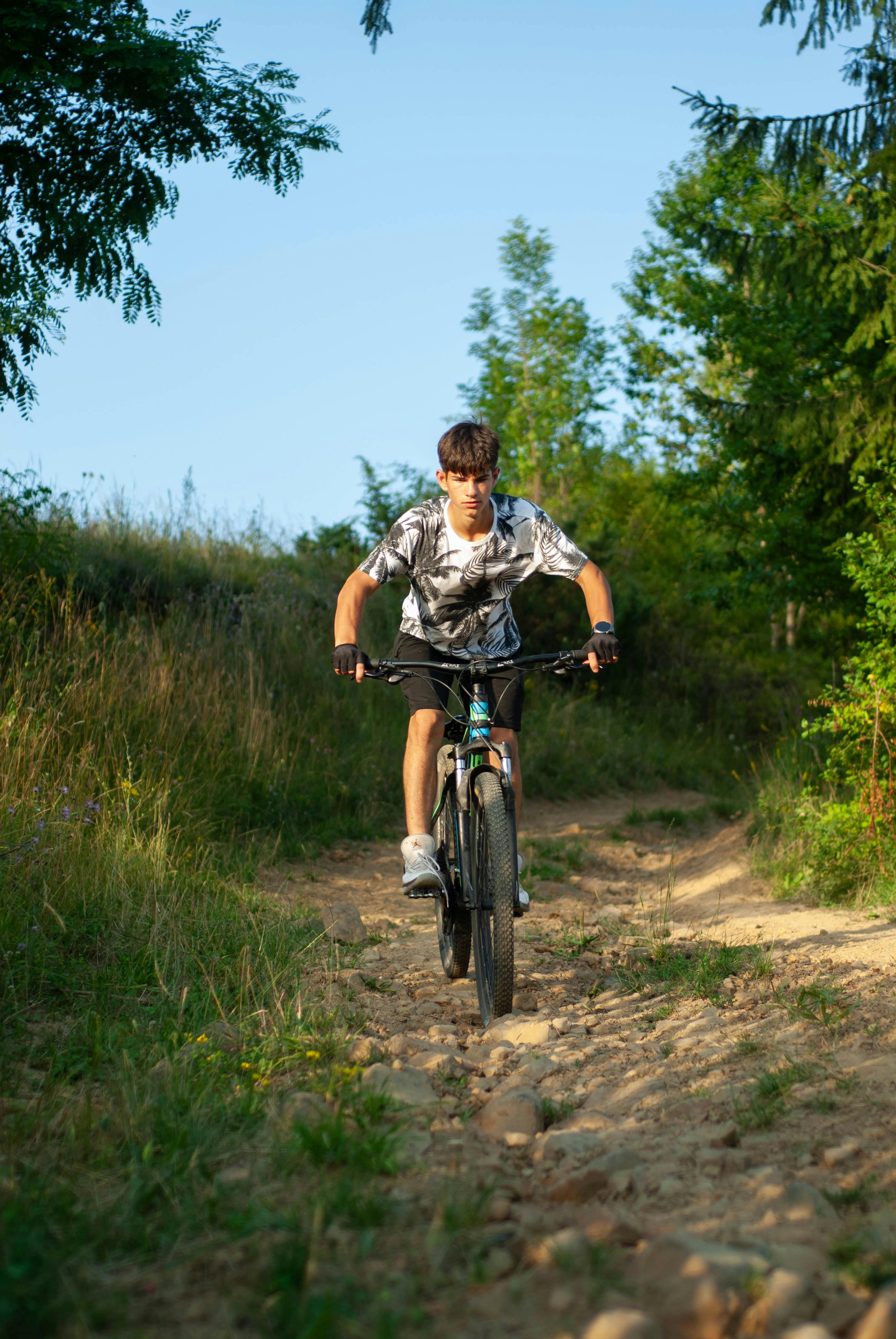 grátis Jovem praticando mountain bike em trilha acidentada na floresta em Sărămaș, Romênia. Foto profissional