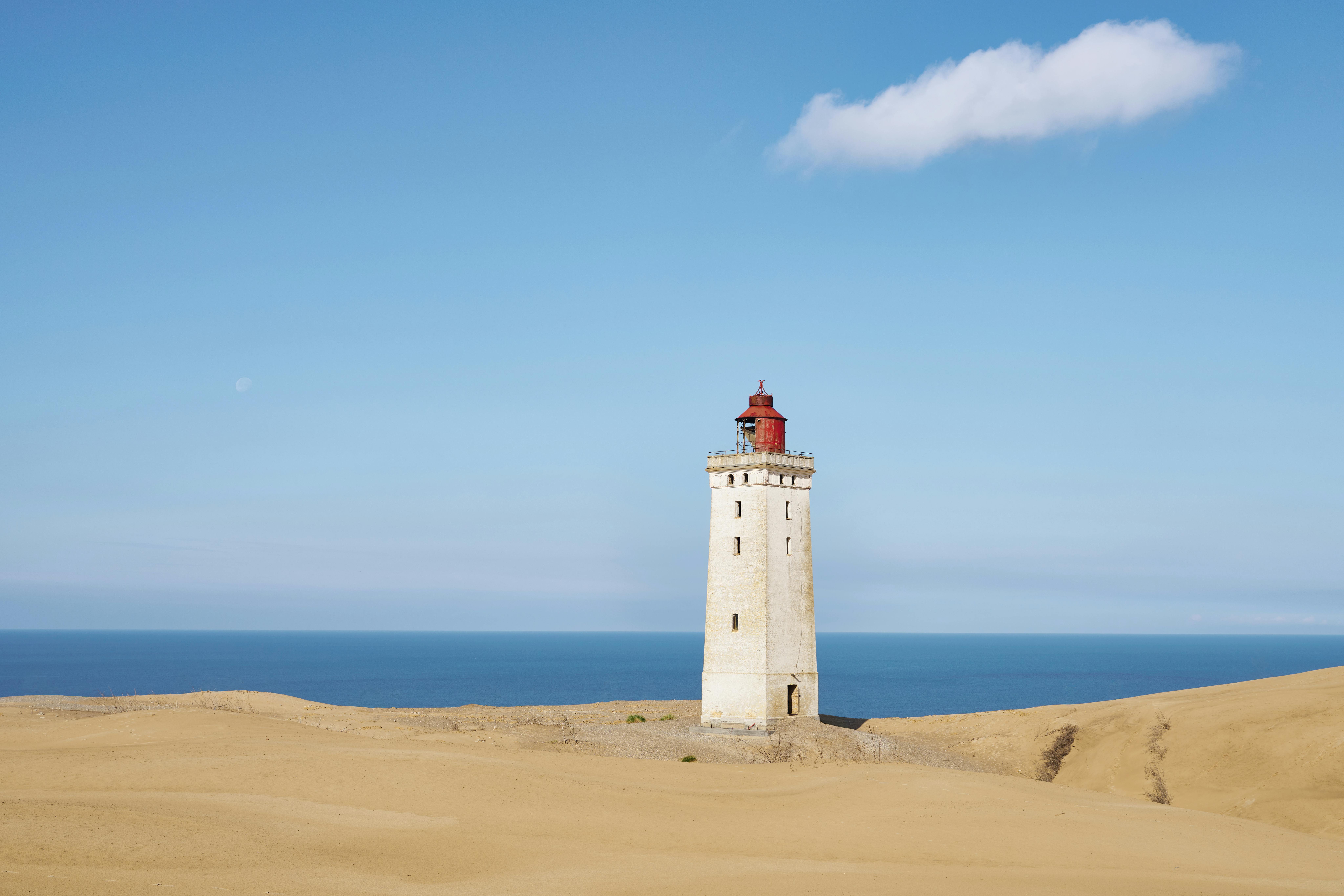 Explore the iconic Rubjerg Knude Lighthouse at Løkken, Denmark, standing tall amidst sandy dunes.