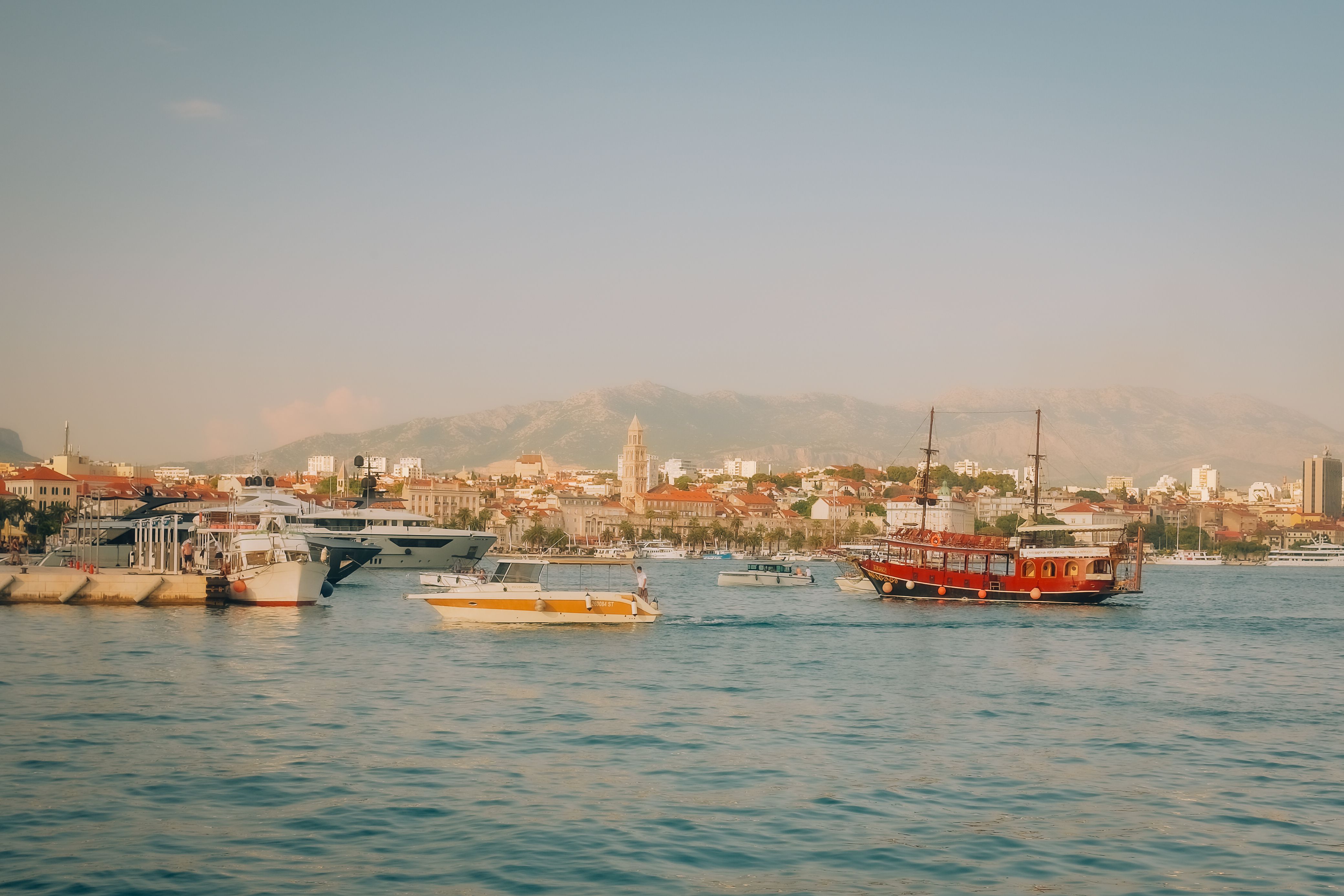 Boats sail near the scenic Split harbor under a clear sky, showcasing Croatia