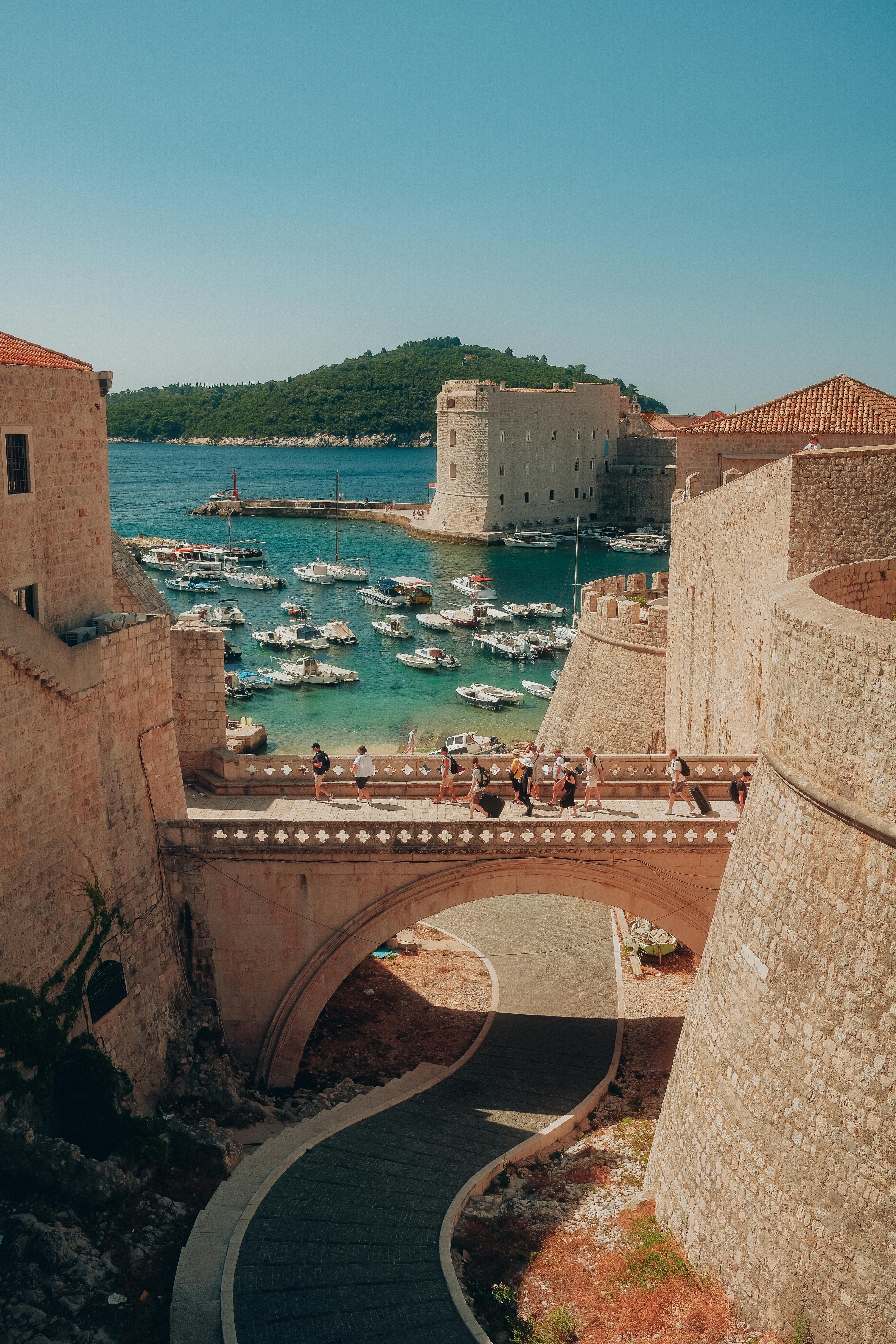 Explore Dubrovnik's iconic harbor with its medieval walls and vibrant blue waters on a sunny day.