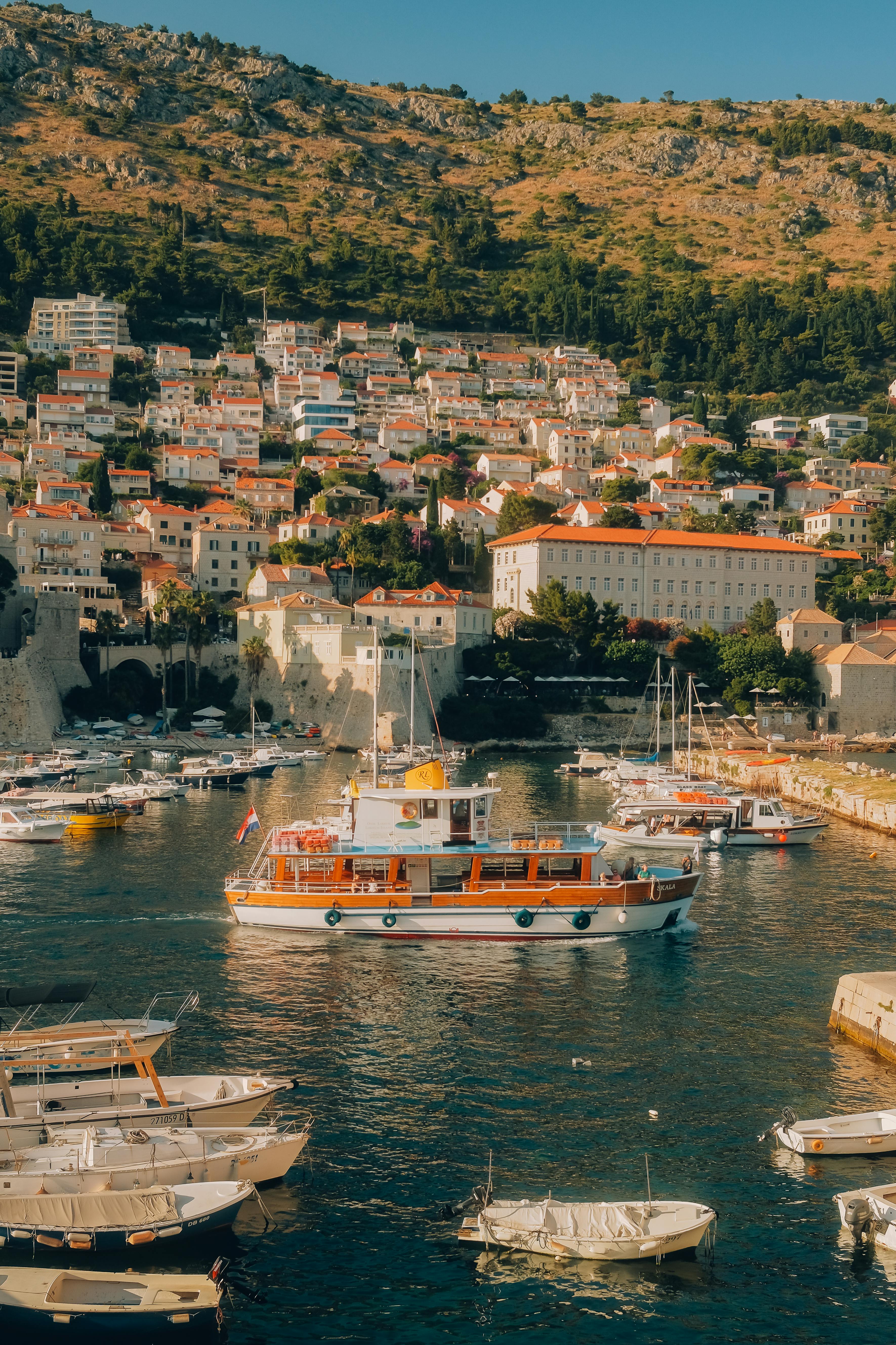 Charming boats docked at Dubrovnik's picturesque harbor, surrounded by historic architecture under a bright summer sky.