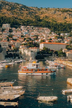Charming boats docked at Dubrovnik's picturesque harbor, surrounded by historic architecture under a bright summer sky.