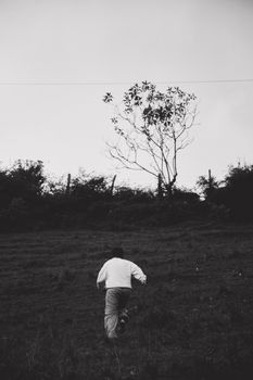 A man walks uphill in the Medellín countryside, captured in a moody black and white photo.