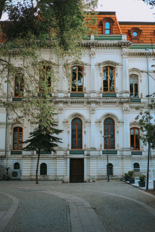 Free Beautiful historical building with intricate architecture surrounded by trees on a sunny day. Stock Photo