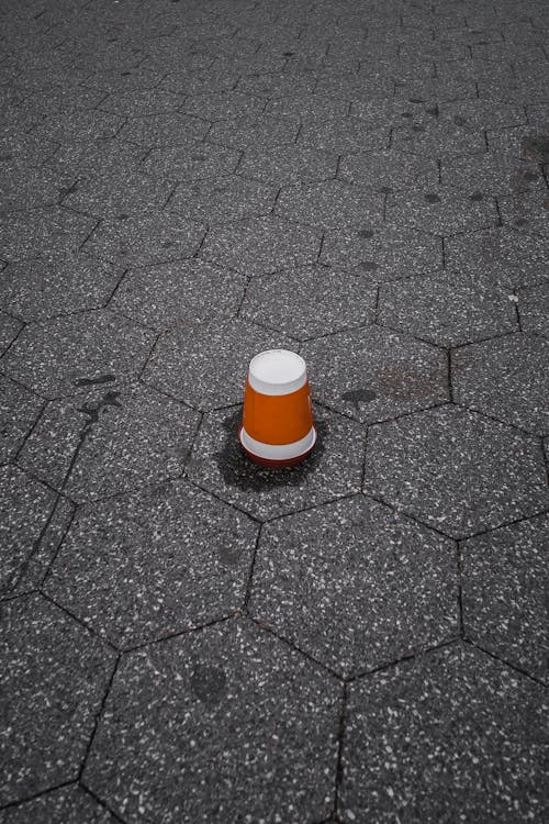 Brown and White Plastic Cup Upside Down on Gray Pavement