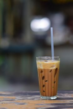 Enjoy a delicious glass of iced coffee with straw on a wooden table, perfect for a summer day.