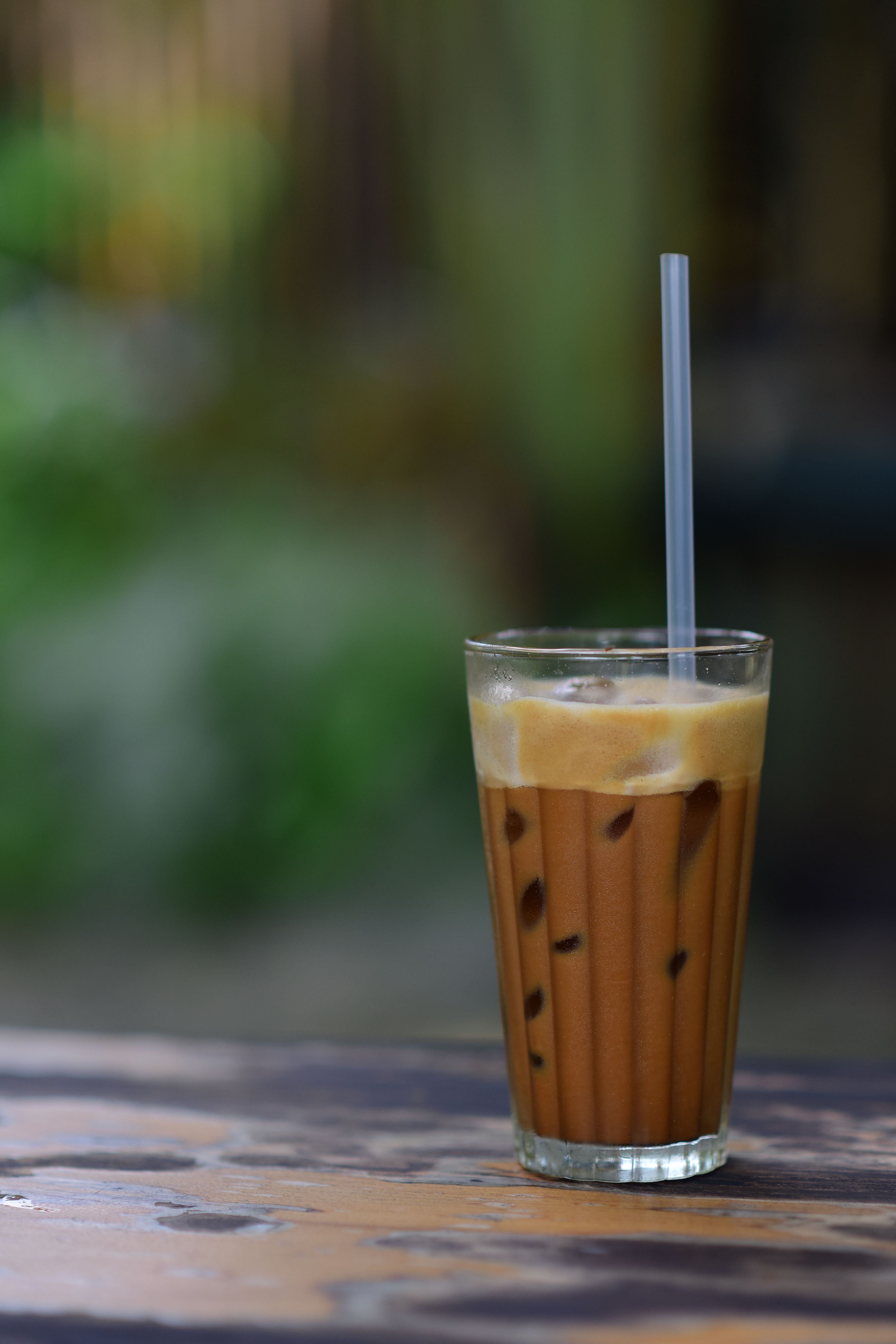 A glass of iced coffee on a wooden table, perfect for a summer day outdoors.
