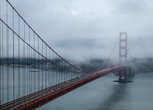 Free Fog rolls over the iconic Golden Gate Bridge in San Francisco, offering a dramatic and moody view. Stock Photo