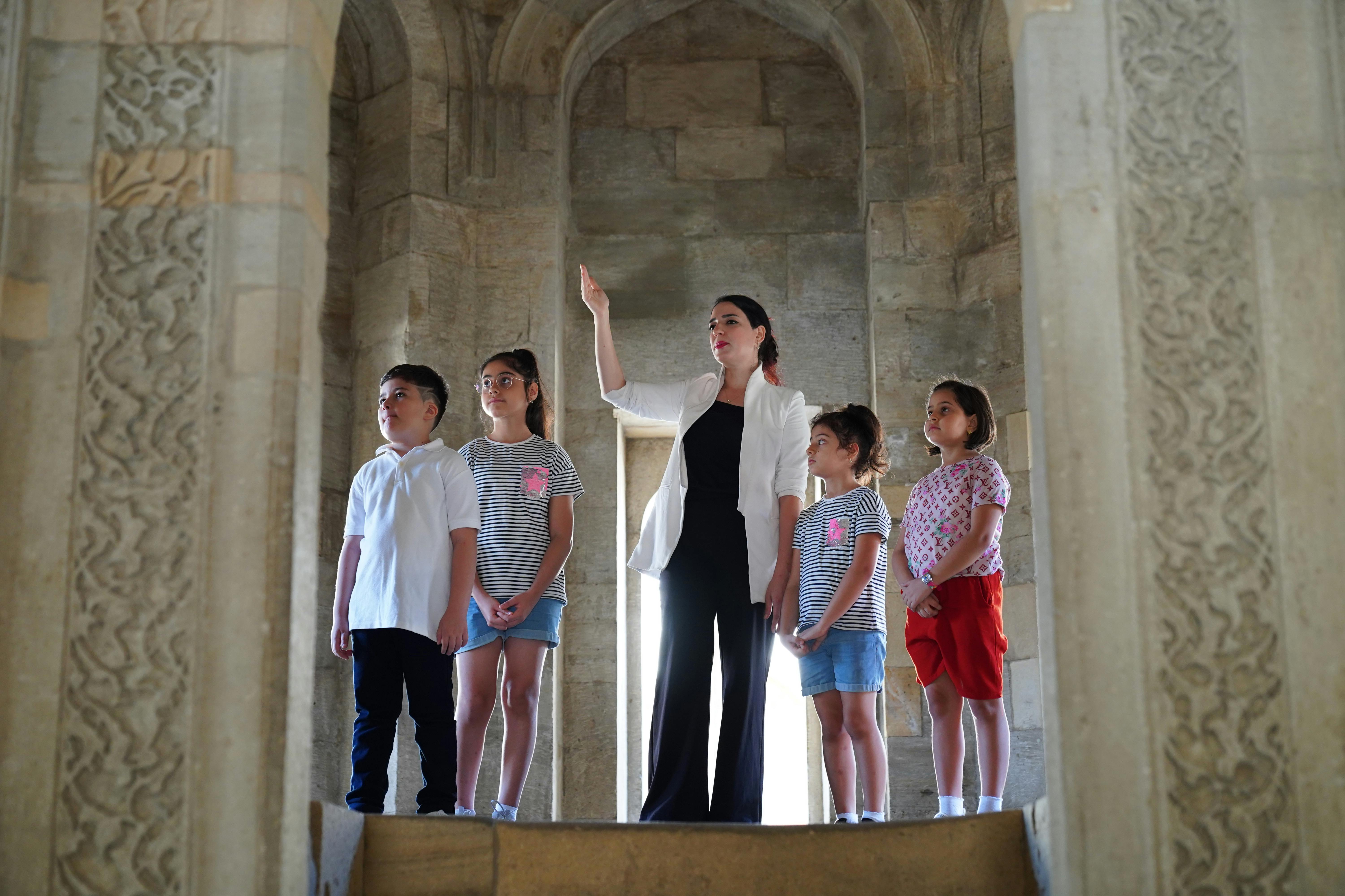 A teacher points out details to four children in a historical building.