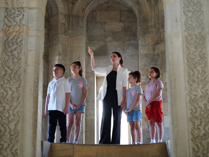A teacher points out details to four children in a historical building - local history lesson plans