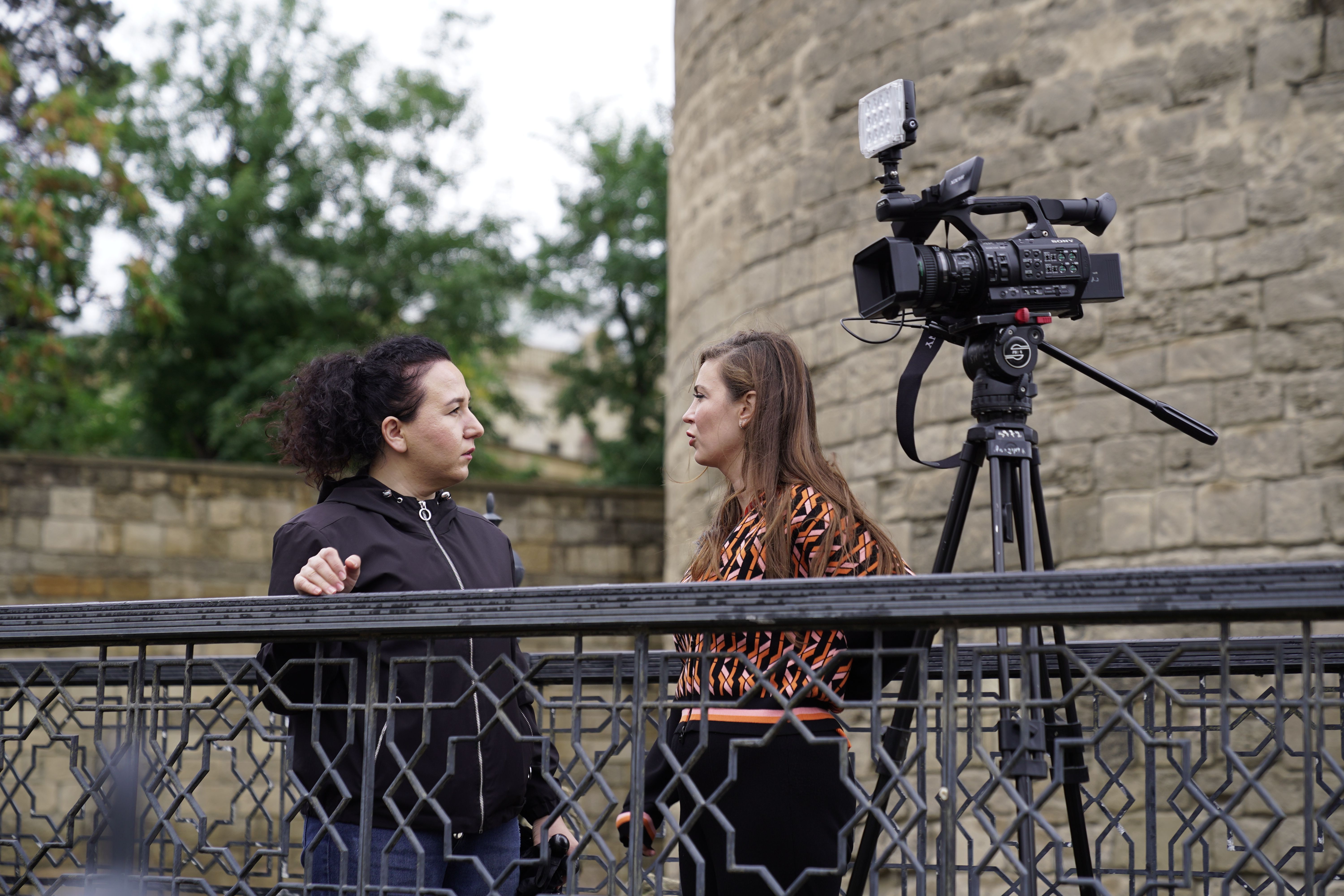 Outdoor Interview with Camera Setup Near Historic Wall · Free Stock Photo
