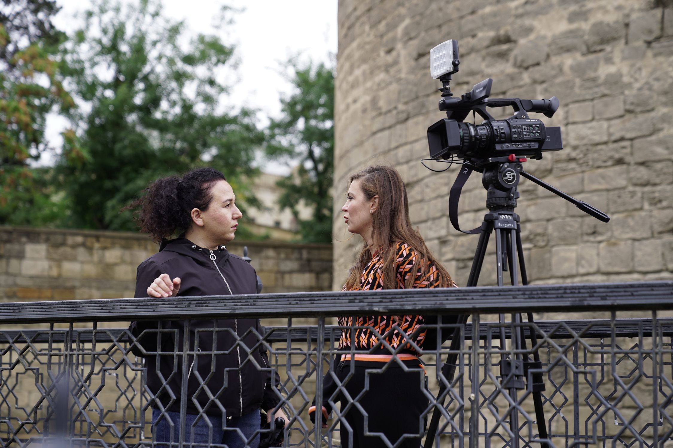 Outdoor Interview with Camera Setup Near Historic Wall · Free Stock Photo