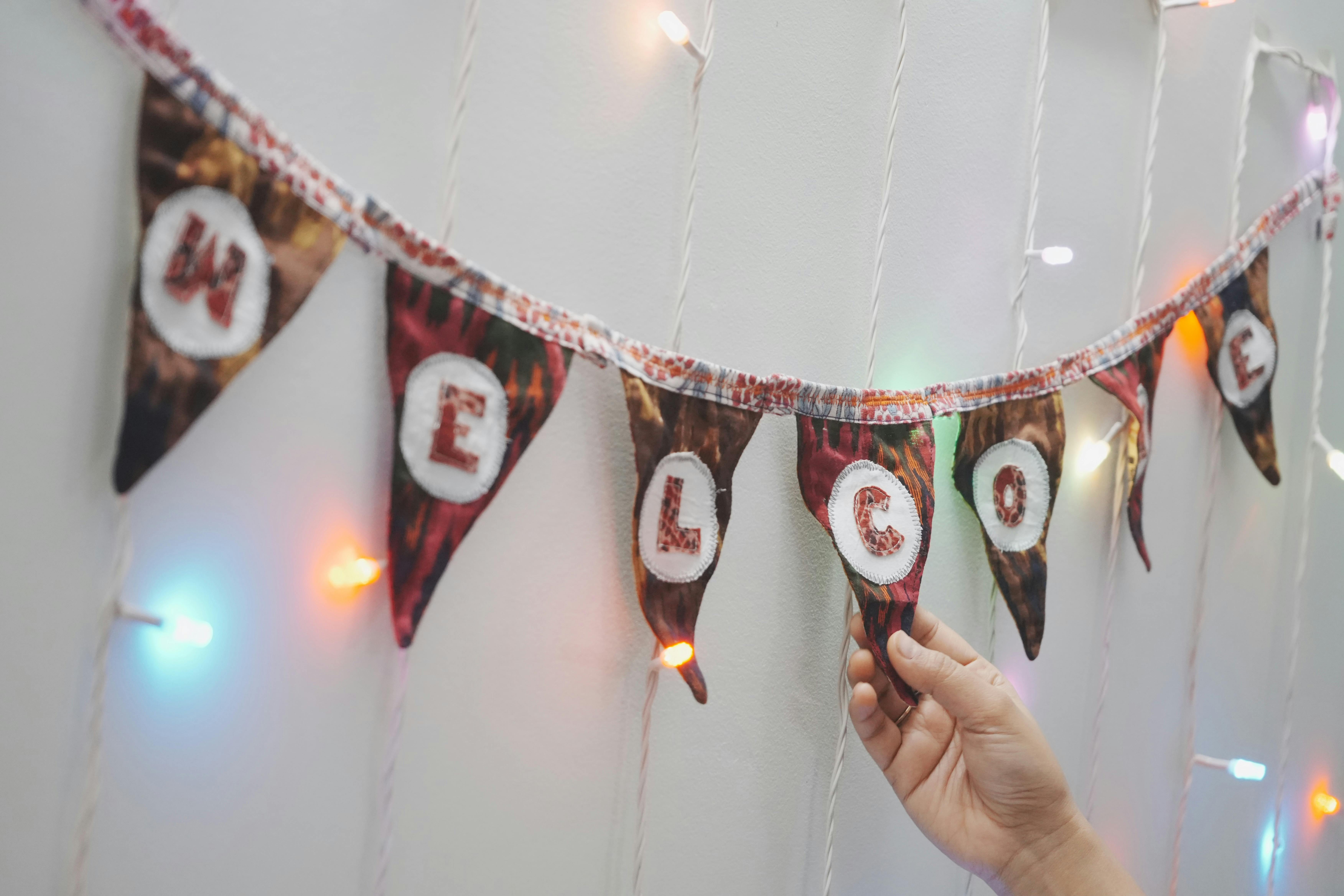 A vibrant 'Welcome' banner with colorful lights and a hand adjusting it, perfect for festive occasions.