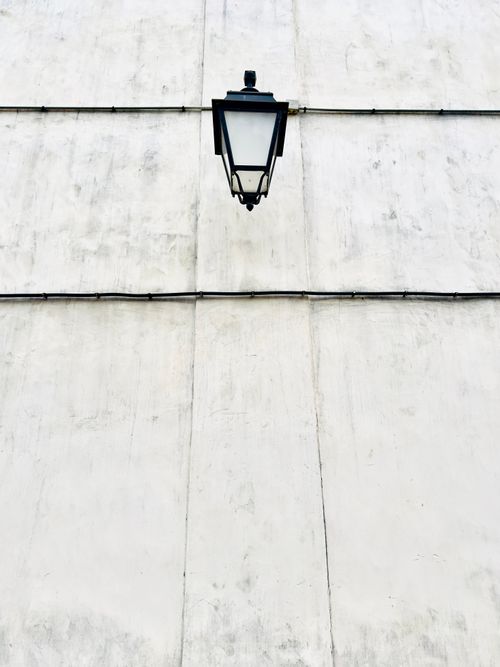 Free A simple and elegant black lantern on a textured white wall, showcasing minimalist design. Stock Photo