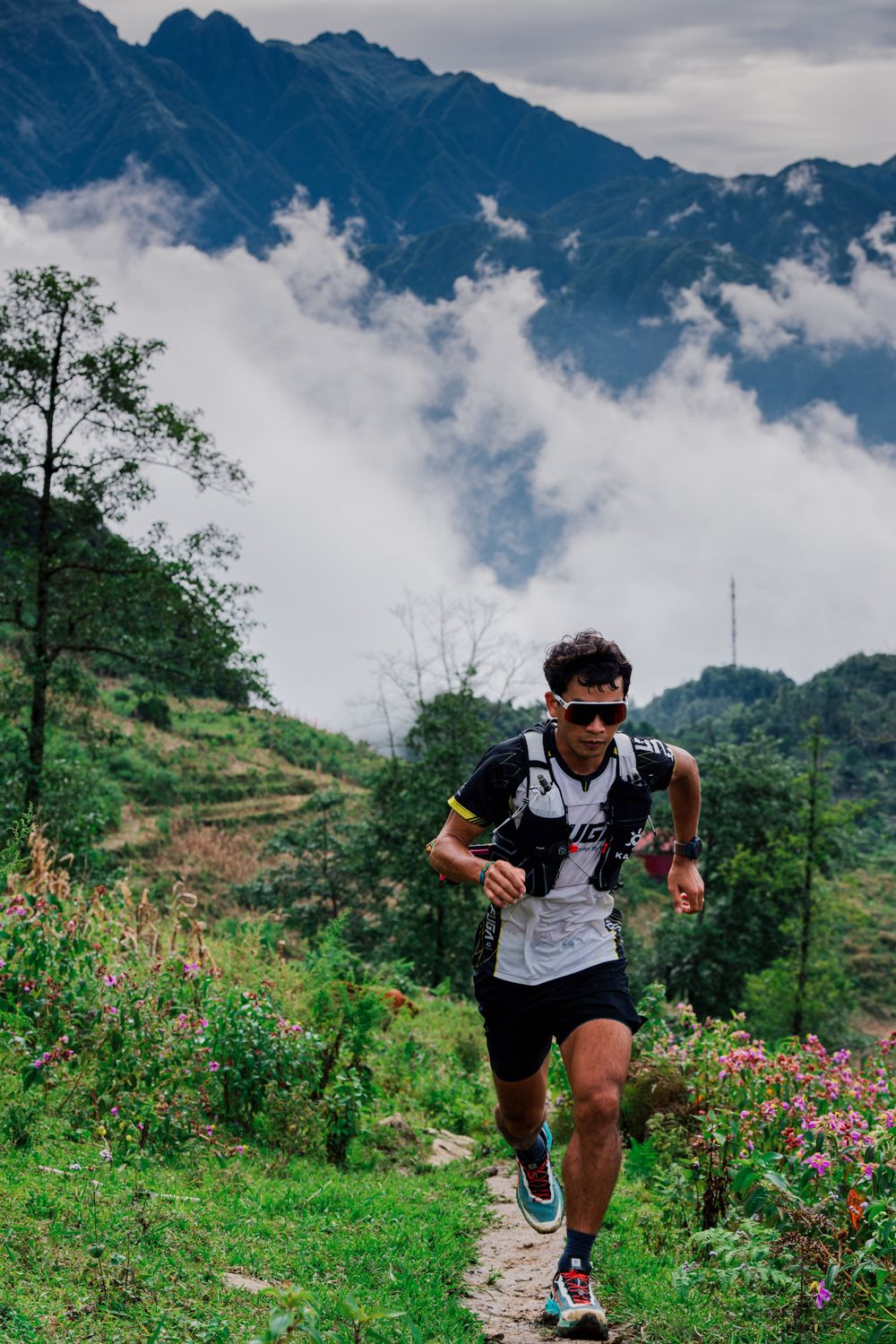 Man running on a mountain trail surrounded by scenic landscapes under cloudy skies