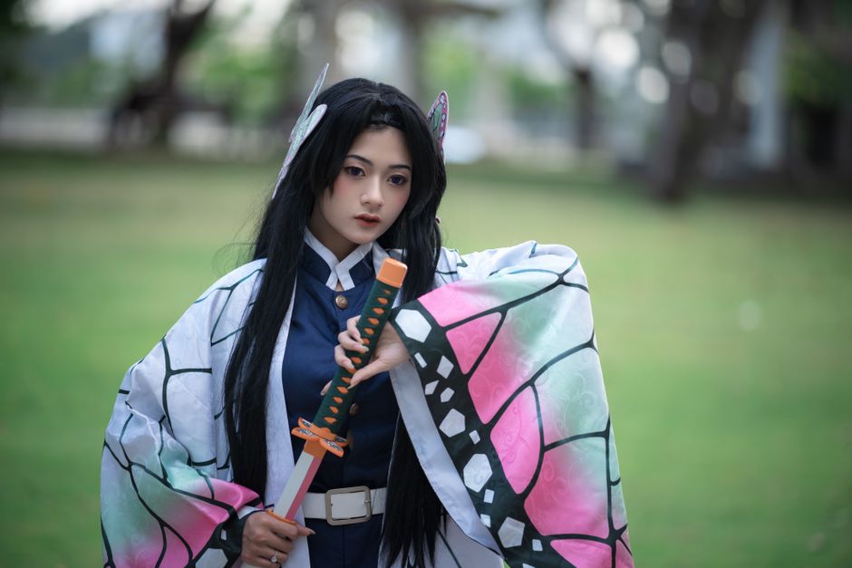 Cosplaying individual dressed as a character from anime, holding a sword in an outdoor setting.