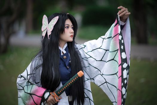 A captivating portrait of a woman in intricate cosplay attire holding a sword outdoors.