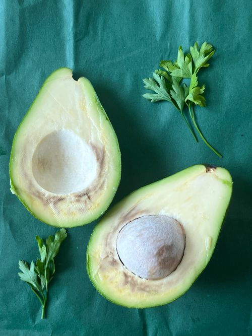 Free Sliced avocado with parsley on green background, highlighting freshness and organic food. Stock Photo