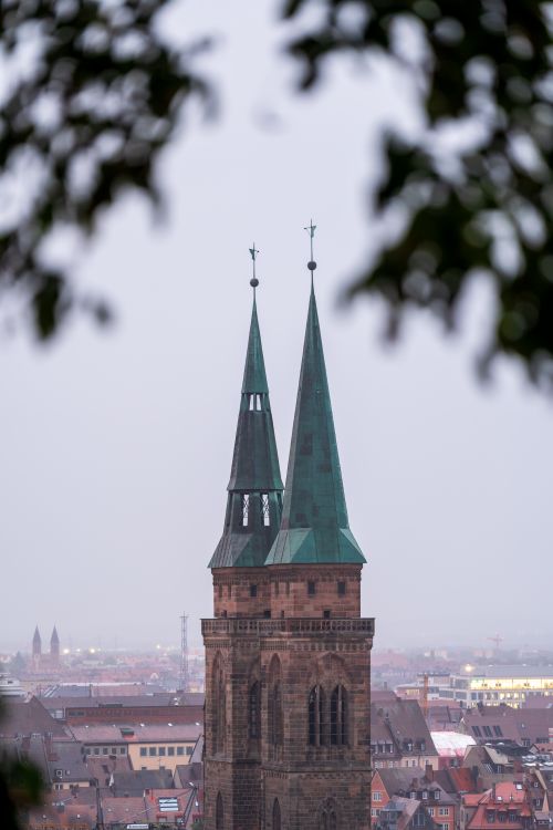 Free Elevated view of a Gothic church's green spires amidst a city skyline at twilight. Stock Photo